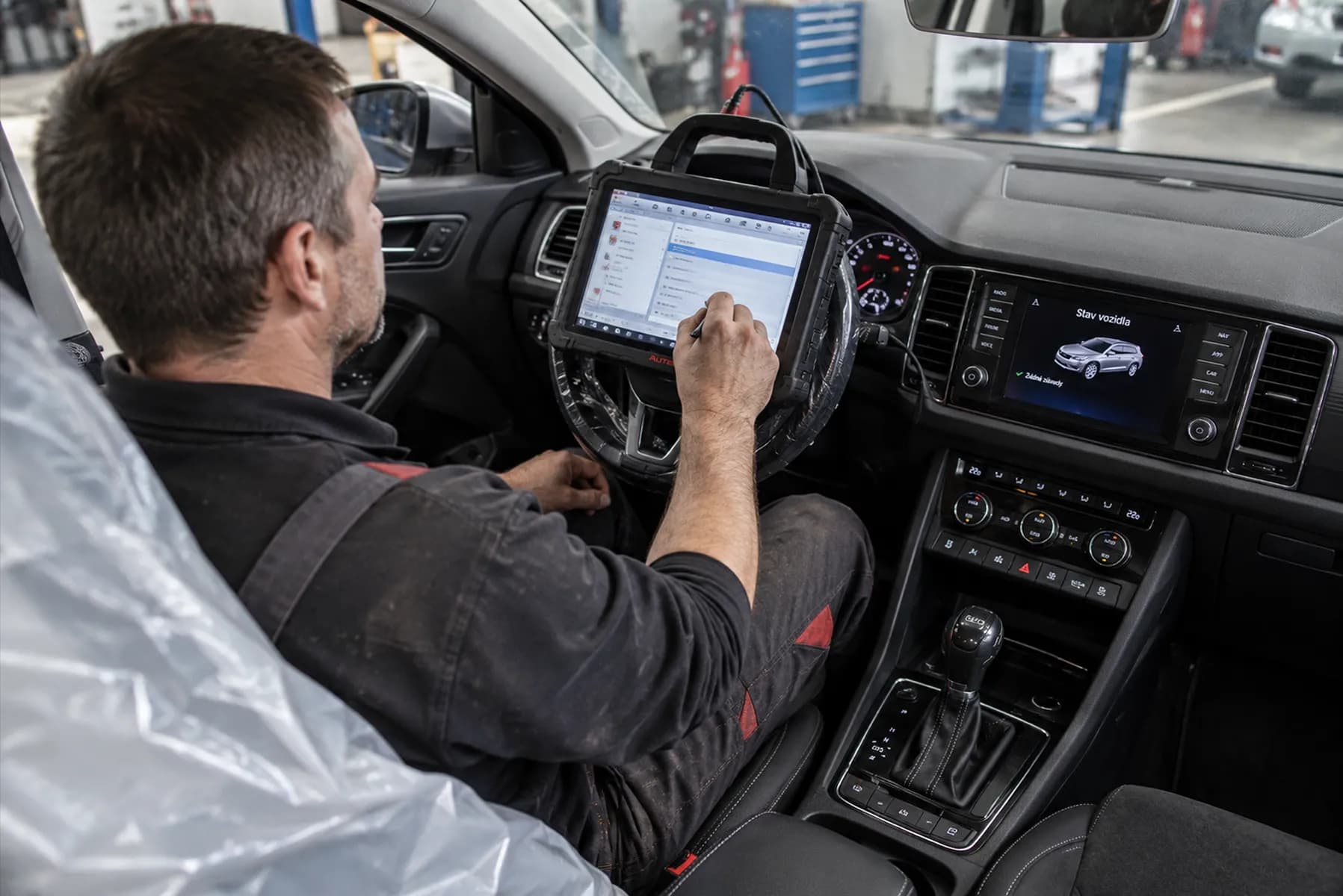 A mechanic using a diagnostic tablet inside a car